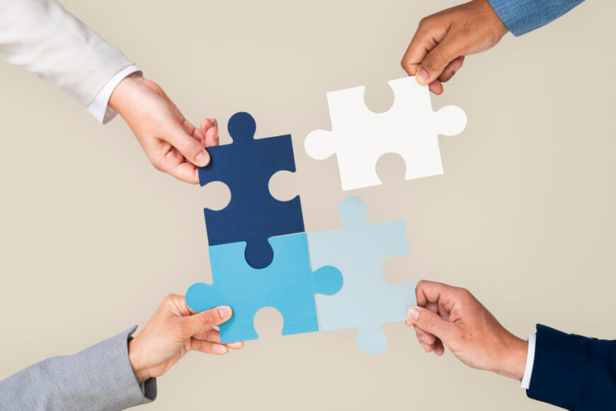 hands holding jigsaw puzzle pieces. 3 of them are joined while the fourth is away from the three.